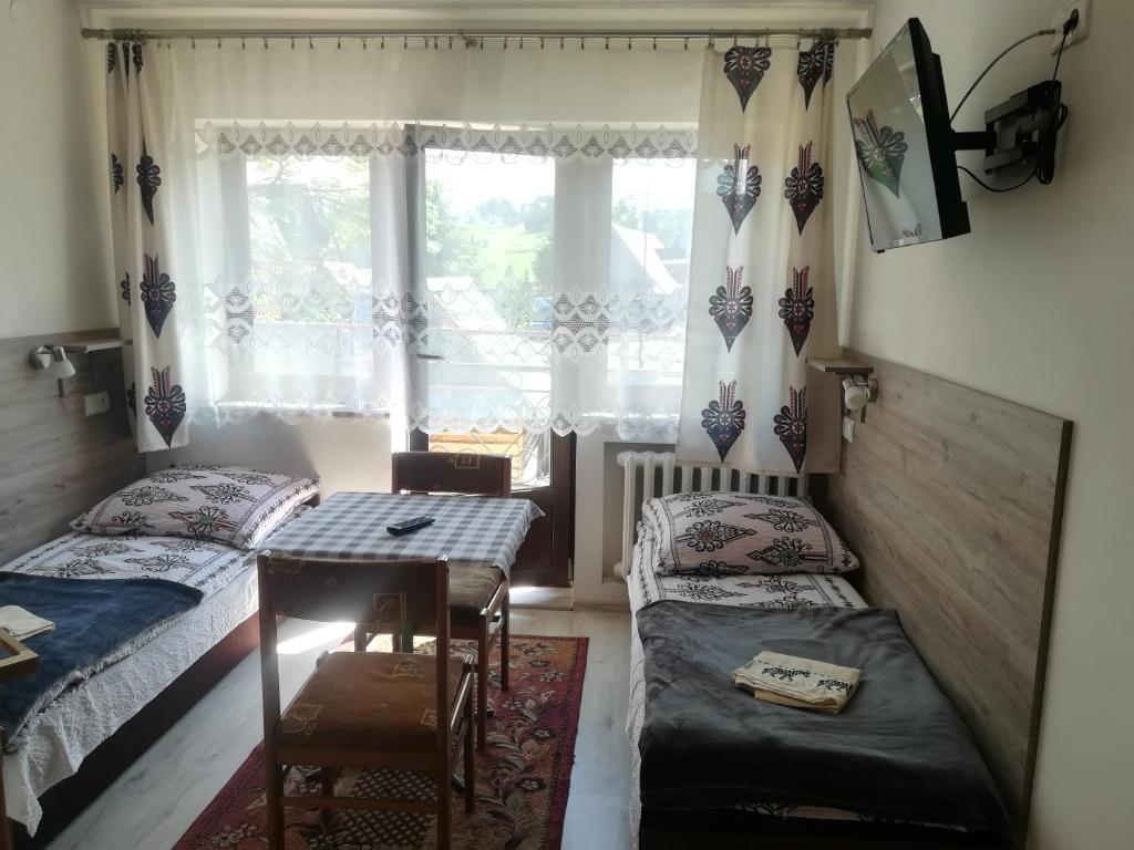 布科维纳-塔钱斯卡Pokoje Gościnne U Babuni的一间卧室设有两张床、一张桌子和一个窗口