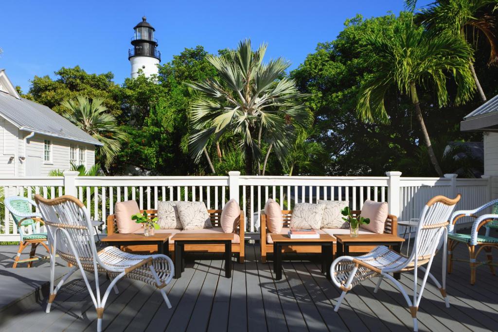 基韦斯特Lighthouse Hotel - Key West Historic Inns的一个带木桌和椅子的甲板和一座灯塔