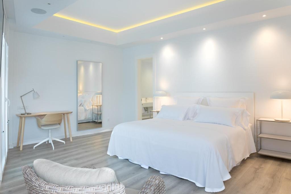 洛斯·亚诺斯·德·阿里丹Lauser City Suites的白色卧室配有白色的床和书桌