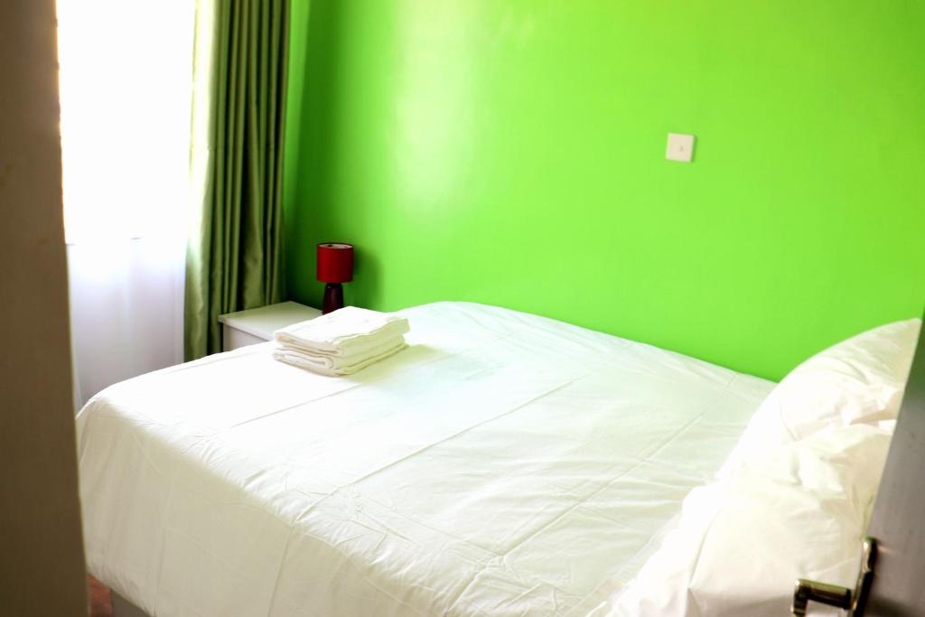 内罗毕Little Green Room Homestay near JKIA Airport & SGR Railway Station的绿色卧室设有一张白色床和绿色墙壁