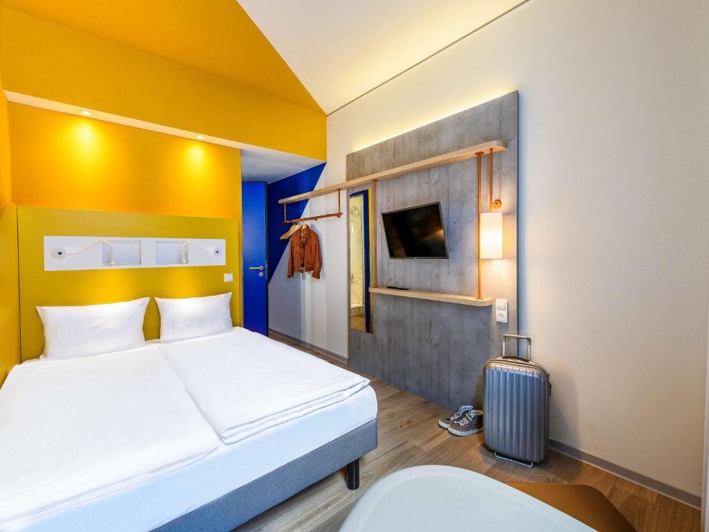 不莱梅ibis budget Bremen City Center的酒店客房,带一张床和行李箱