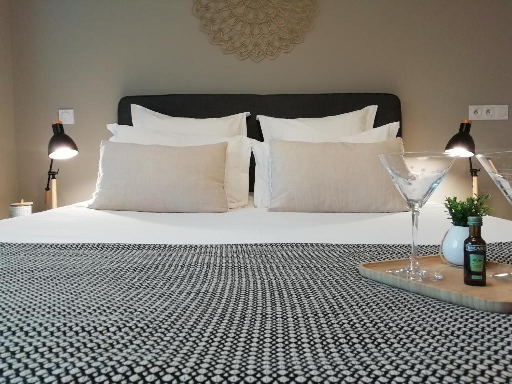 普罗旺斯艾克斯Sweet Home studio Aix en Provence, terrasse, piscine, resto,的一张带白色枕头和一杯葡萄酒的床