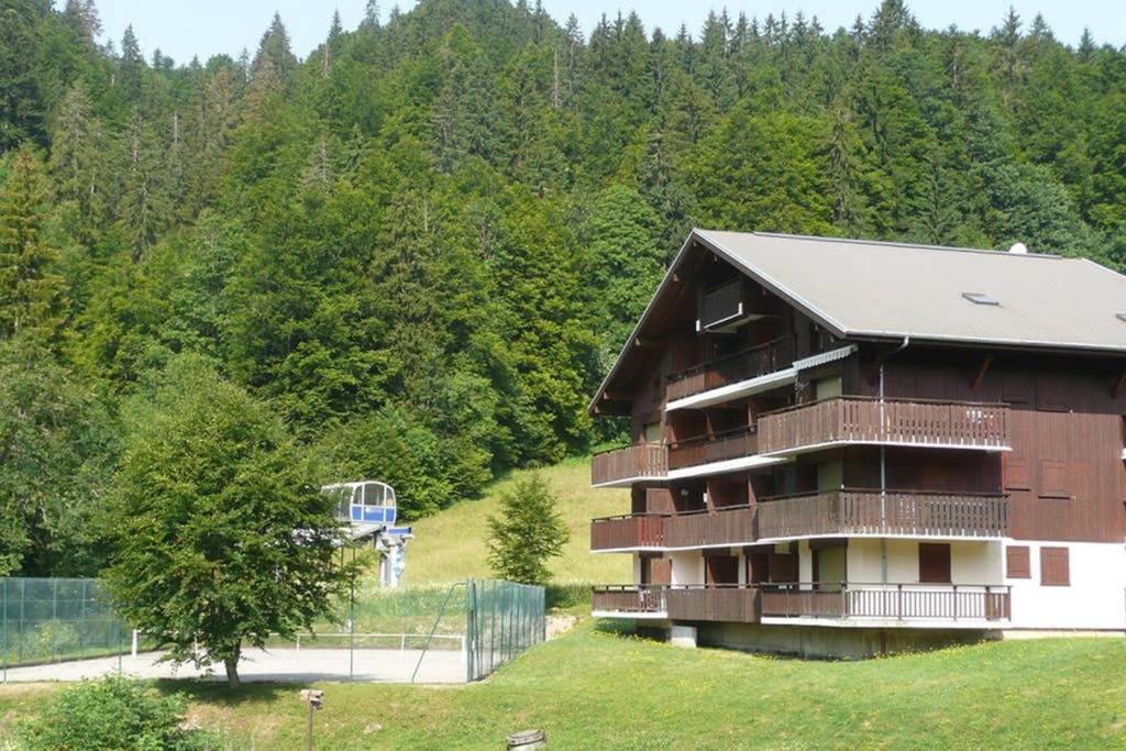 贝勒沃Les Chalets du Pounant - Alpes du Léman的森林前方有篮球架的建筑物