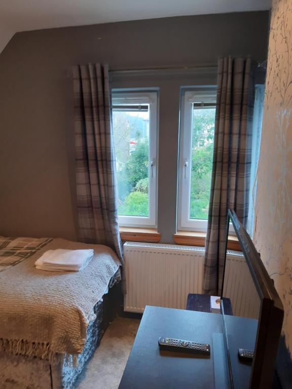 布罗迪克Ardgowan Cottage的一间小卧室,配有床和2个窗户