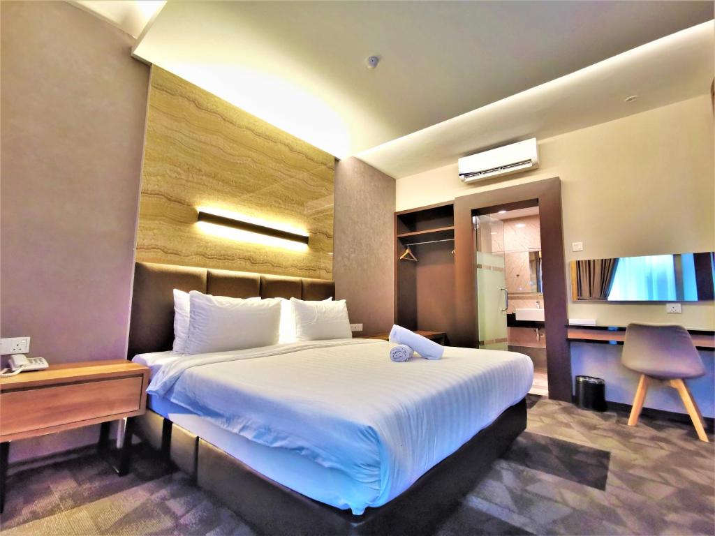 新山Prestigo Hotel - Johor Bharu的酒店客房设有一张大床和一张书桌。