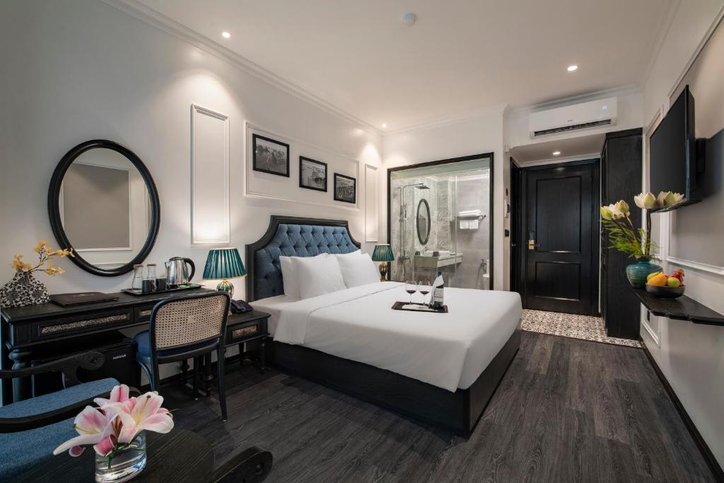 下龙湾Ha Long Essence Hotel的一间卧室配有一张床、一张书桌和一面镜子