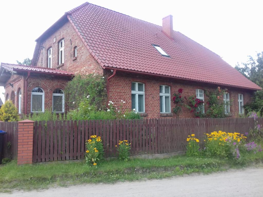GórkiWczasy na Kaszubach的红砖房子,带围栏和鲜花