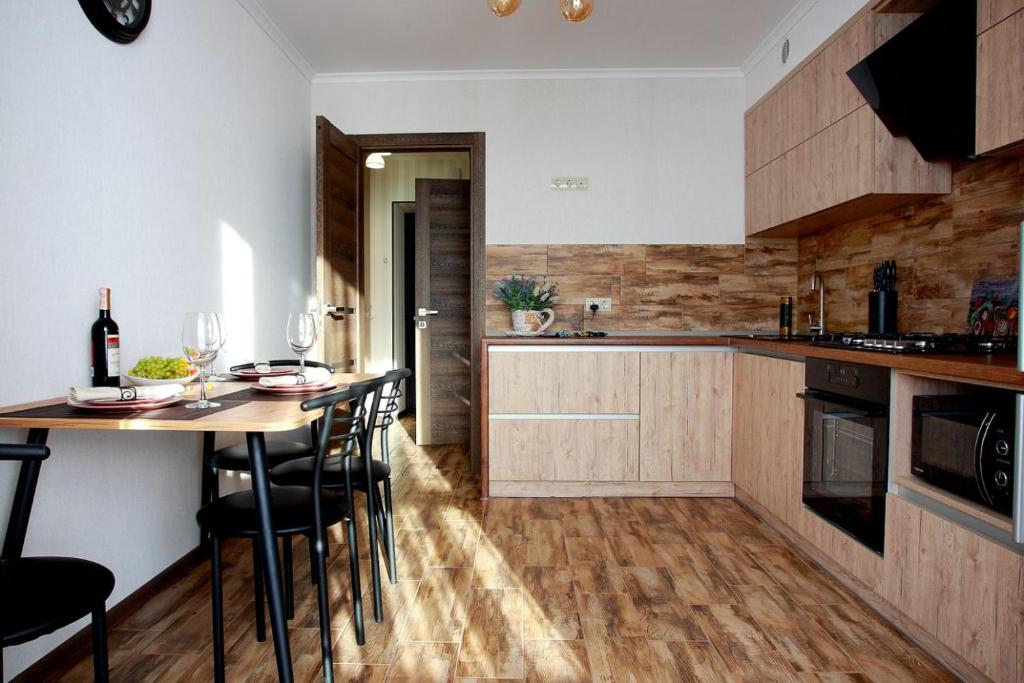 文尼察Apartament Vasilya Porika 48 Street Vinnytsya,Ukraine的厨房配有木制橱柜和桌椅