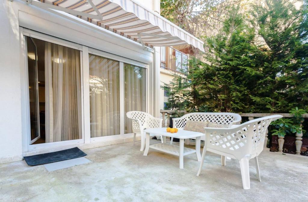 贝西奇Mandarin Apartments的阳台设有带白色椅子和桌子的庭院。