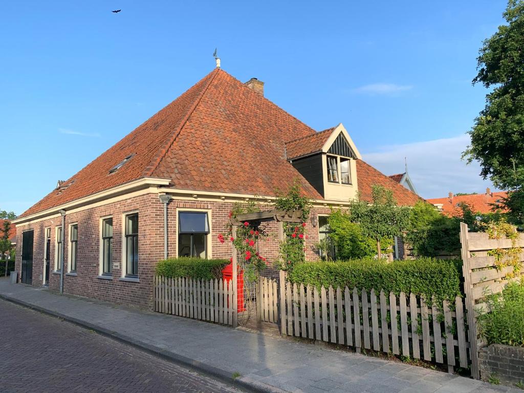 埃丹"De Walvisch", appartement in authentieke boerderij的红门和栅栏的砖屋
