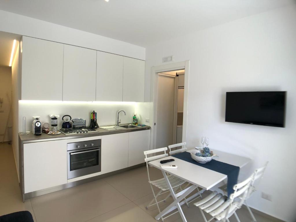 拉古萨码头Vista Mare Apartment con parcheggio privato的厨房配有白色橱柜和桌椅