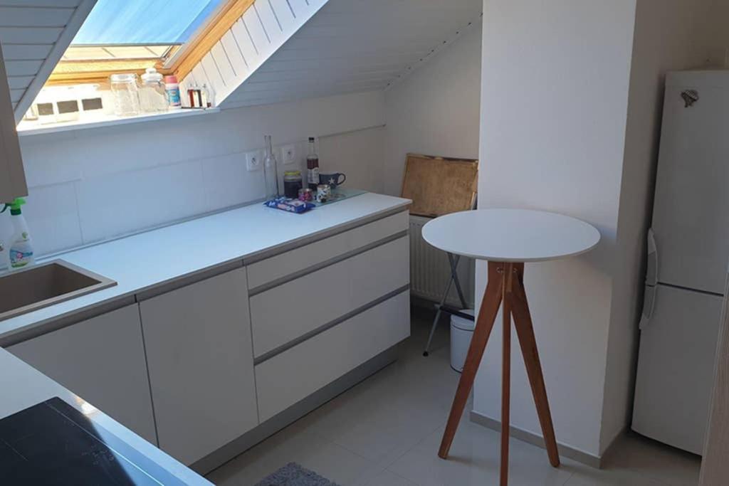 科希策Útulný apartman Kmeťova的白色的厨房配有桌子和白色冰箱