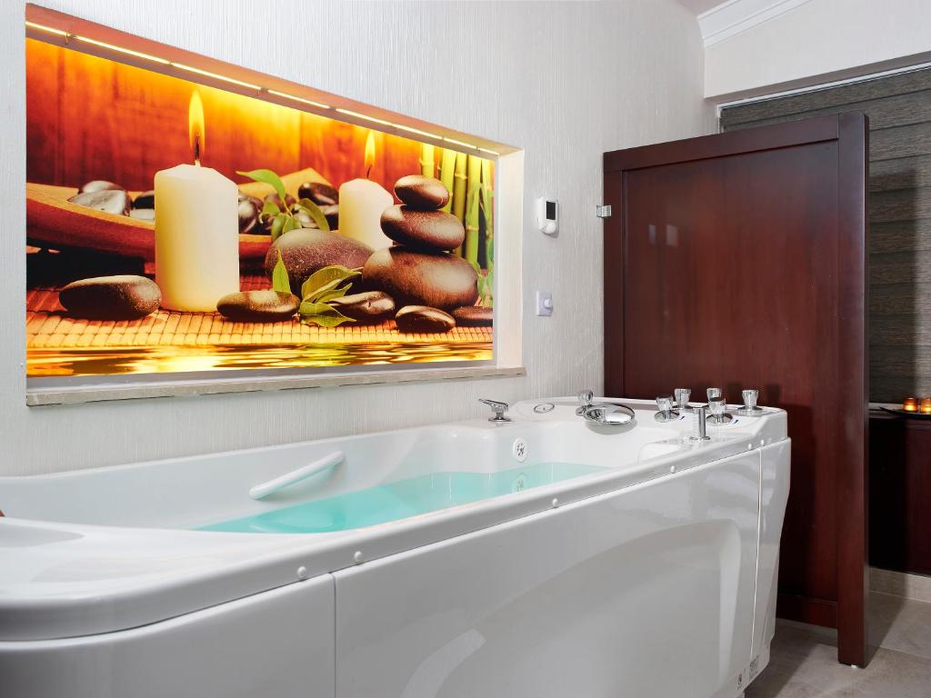 卡罗维发利埃莱凡特EA酒店的浴室设有白色浴缸和墙上的绘画作品