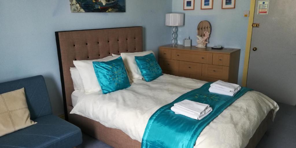 布莱克浦Northdene Theatre Hotel的一间卧室配有一张带蓝色枕头的床和一张蓝色椅子