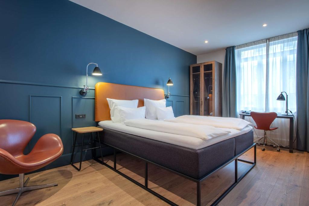 哥本哈根The Huxley Copenhagen, BW Premier Collection的一间卧室设有一张大床和蓝色的墙壁