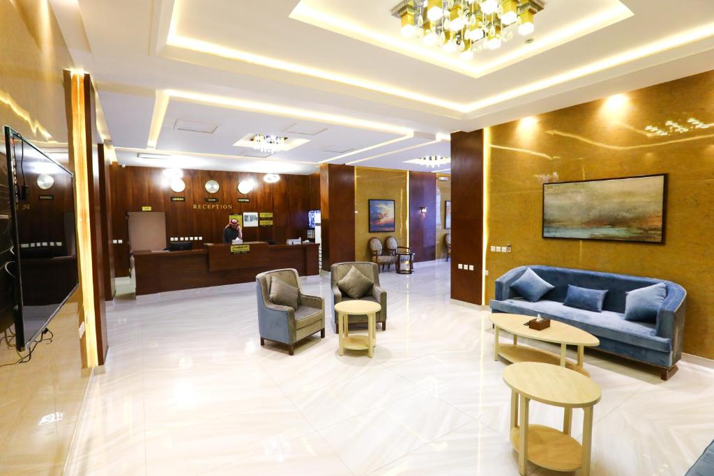 利雅德Qasr Alhanen Furnished Apartments的大堂设有蓝色的沙发、椅子和一张桌子