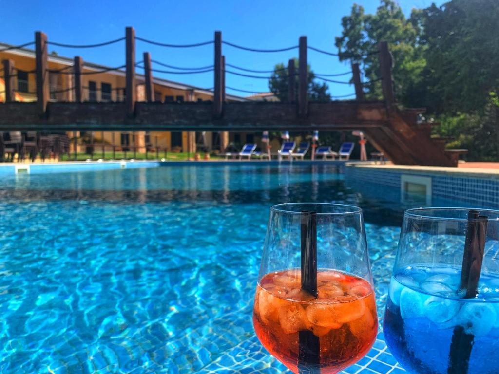 瓦雷多利亚Hotel La Ciaccia的两个玻璃杯坐在游泳池旁的桌子上