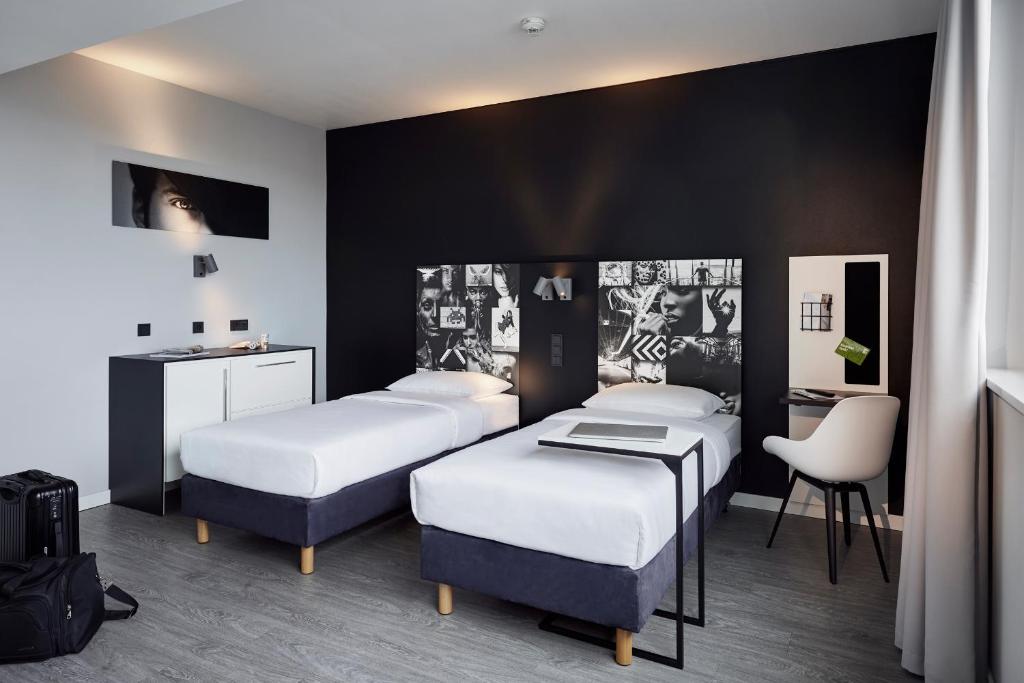 比勒费尔德LÉGÈRE EXPRESS Bielefeld的客房设有三张床、一张桌子和一把椅子。