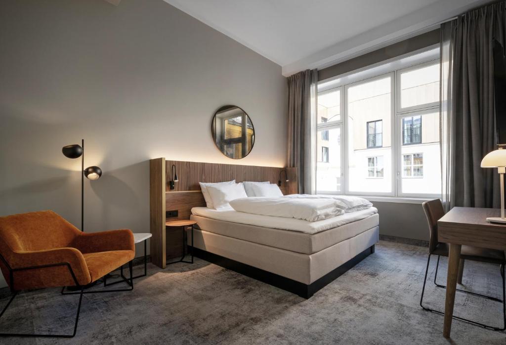 奥斯陆Karl Johan Hotel的配有一张床和一把椅子的酒店客房