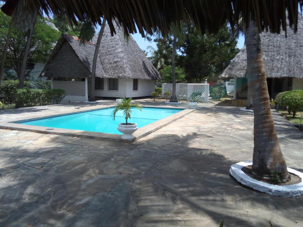 迪亚尼海滩Glory Ocean Villas - Diani的一座带房子和棕榈树的游泳池
