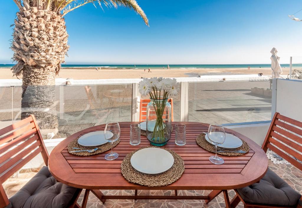 宏达海滩Luxury Suite Sea Front II的海滩上一张带盘子和玻璃杯的木桌