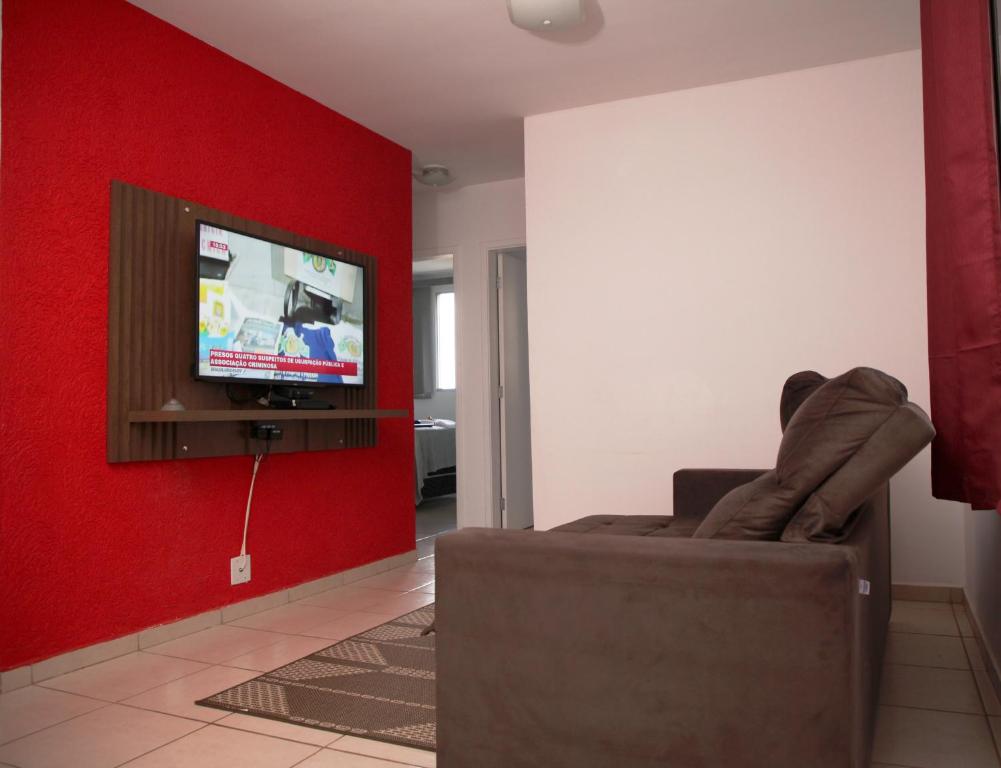 乌贝拉巴Apartamento Aeroporto/ Uniube的客厅配有沙发和红色墙壁上的电视