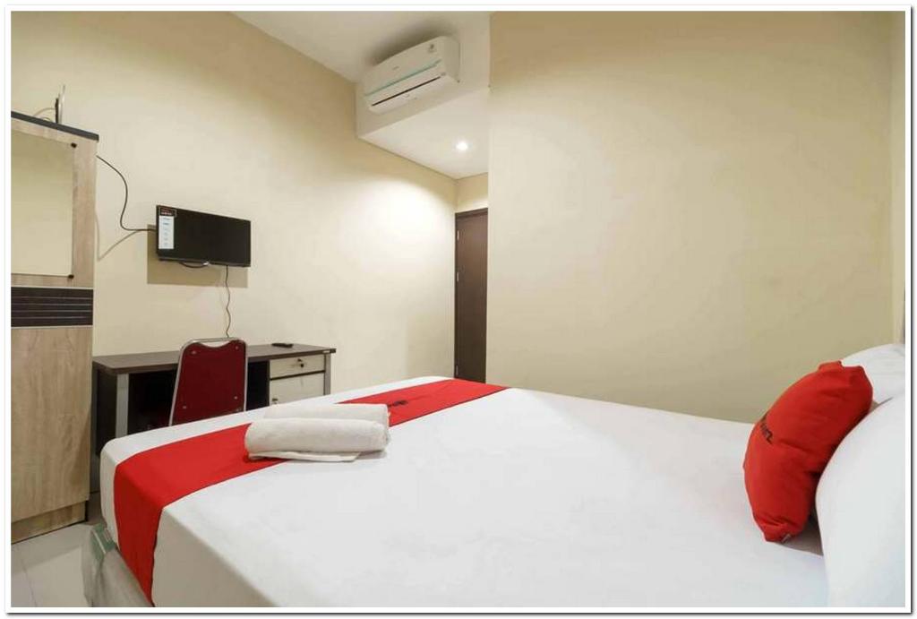 雅加达KoolKost At Karang Tengah Tangerang的卧室配有白色的床和红色椅子
