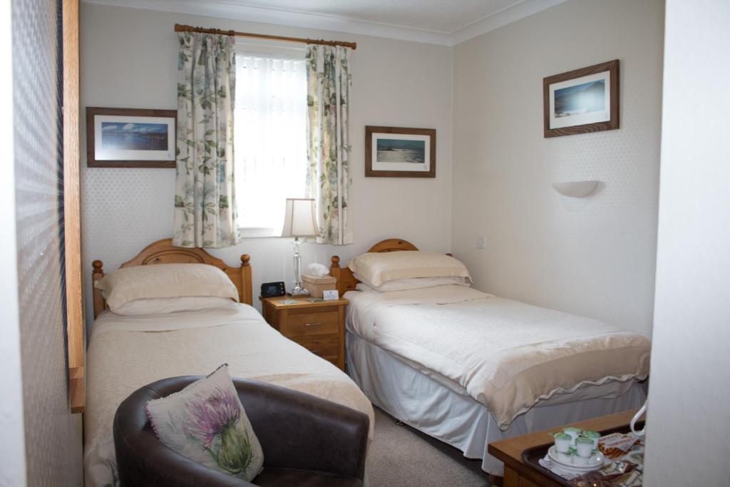 爱丁堡Whitecroft B&B的一间卧室设有两张床、一把椅子和一个窗户。