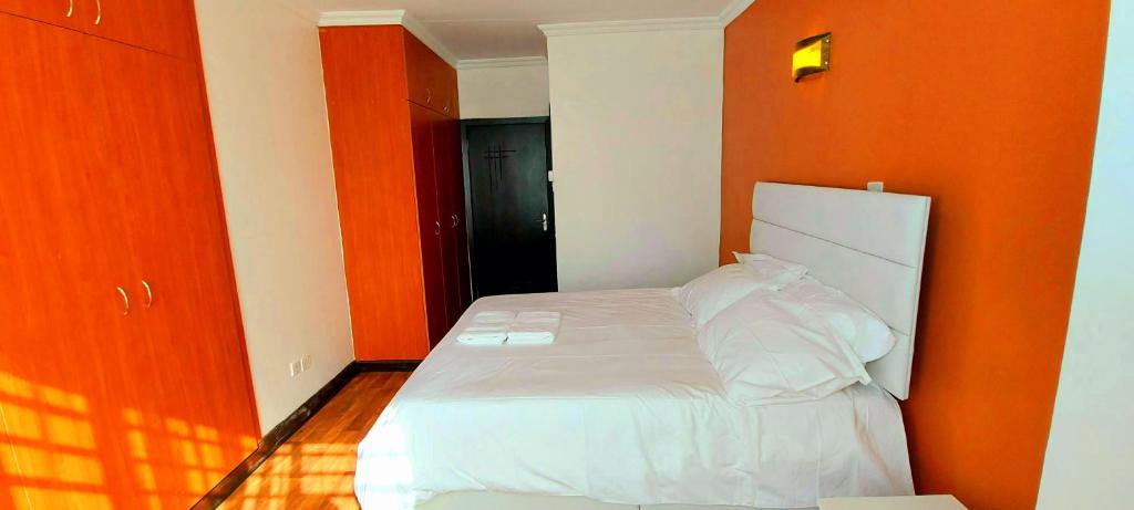 内罗毕Pleasant Nest Homestay near JKIA Airport and SGR Station Nairobi的橙色墙壁间的一张床位