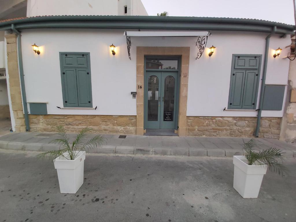 拉纳卡Magdalene's City House Inn的一座建筑,有两扇绿门和两株盆栽植物