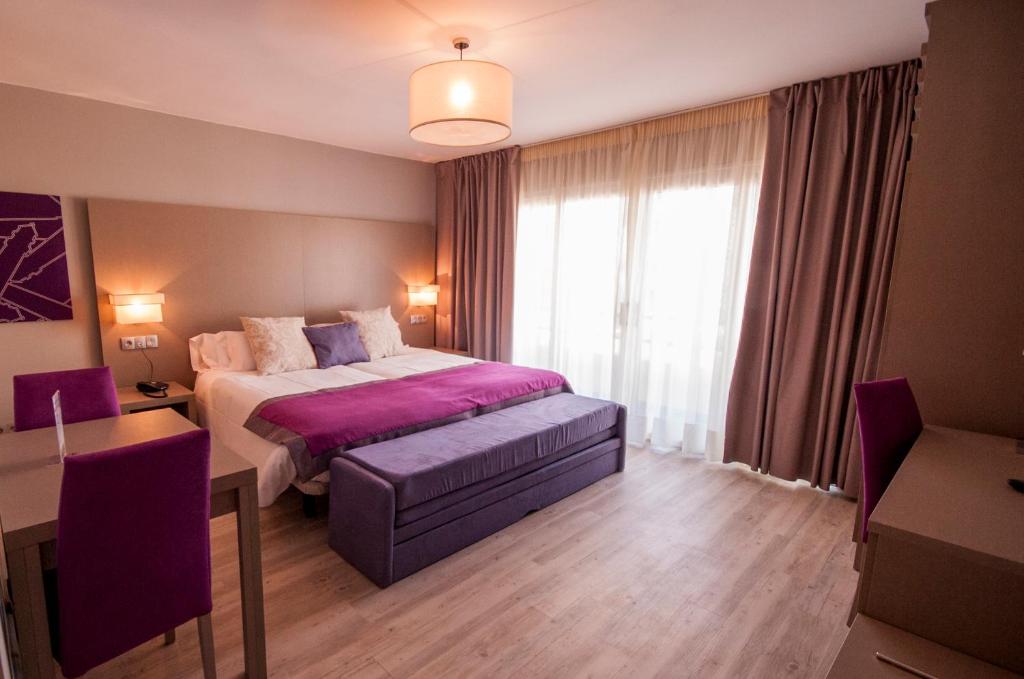 马贝拉埃尔法罗马贝拉酒店的一间卧室配有一张床、一张桌子和一个窗户。