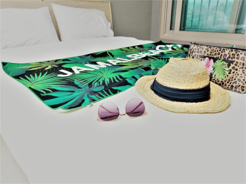 济州市ARA Palace Hotel的一张带帽子和太阳镜的床