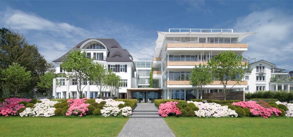 康斯坦茨RIVA - 博登湖酒店的一座白色的大建筑,前面有鲜花