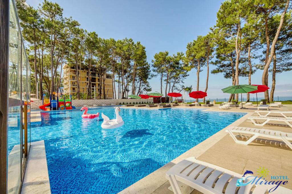 谢赫维蒂利Mirage Hotel的度假村内带天鹅和充气器的游泳池