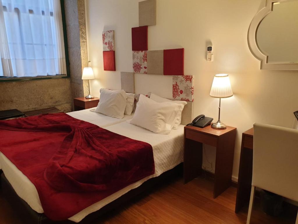 波尔图波尔图黎各宾馆的一间卧室配有一张带红色毯子的大床