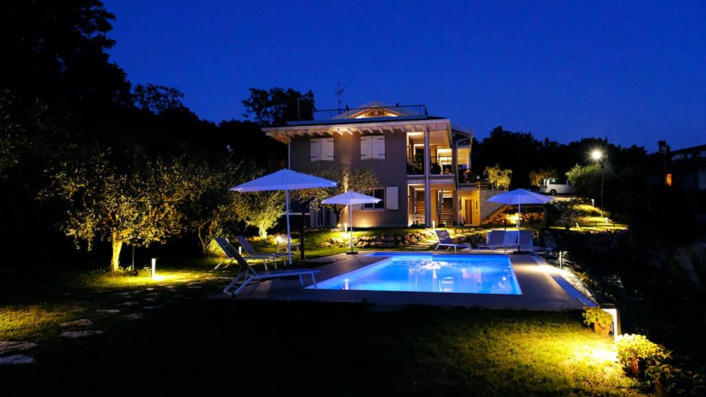 卡普里诺韦罗内塞Villa Nina - Apartments & Relax的一座晚上设有游泳池的房子
