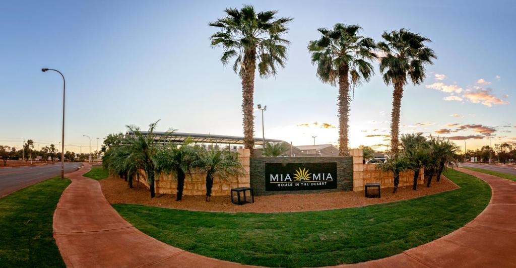 纽曼沙漠米娅米娅之家旅馆的标志前有棕榈树的公园