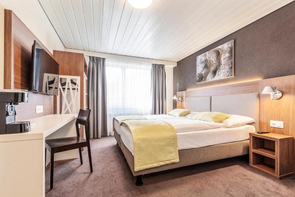 马蒂尼威尔Campanile Martigny的配有一张床和一张书桌的酒店客房