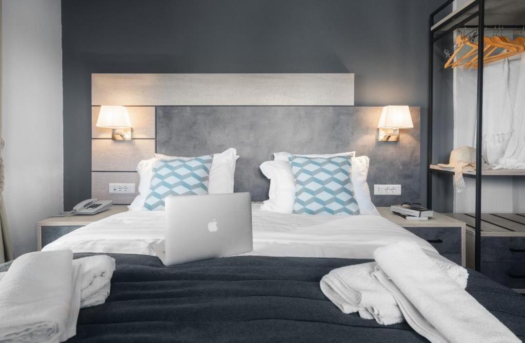 新马尔马拉斯Meliton Inn Hotel & Suites by the beach的一间卧室配有一张带笔记本电脑的床