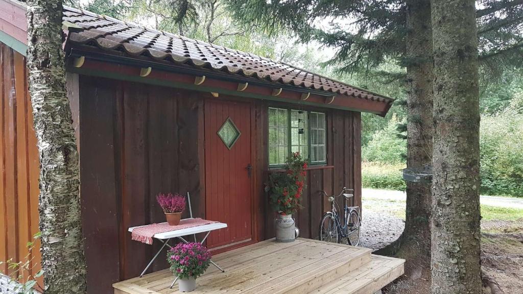 SolsemIdyllisk liten hytte的一个小红棚,上面有桌子和鲜花