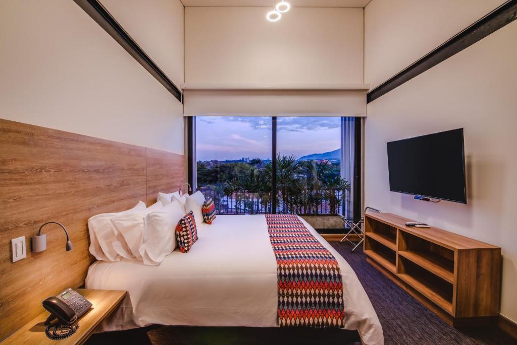 卡利Alko Hotel Integrado的一间酒店客房,设有一张大床和一个大窗户