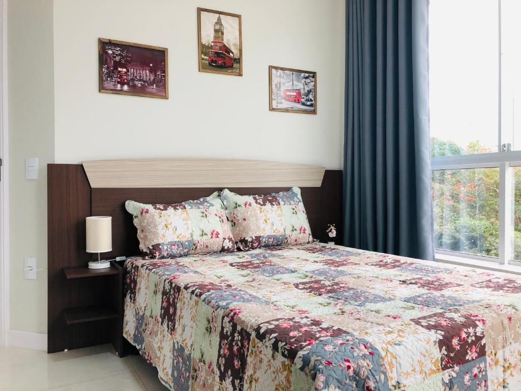 邦比尼亚斯Residencial Spader - Bombinhas的一间卧室配有一张带被子的床和一扇窗户
