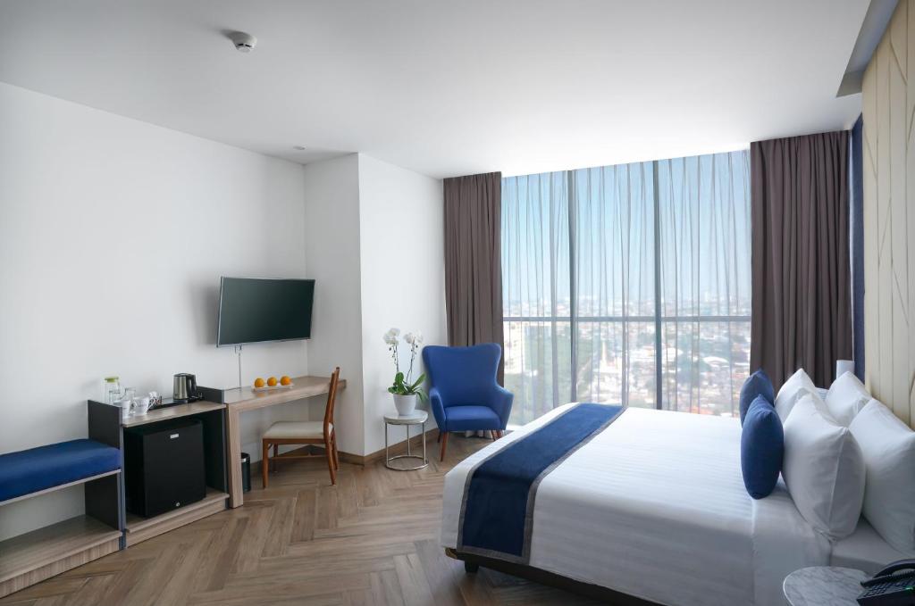 雅加达ASTON Kemayoran City Hotel的酒店客房设有一张床、一张书桌和一台电视机。