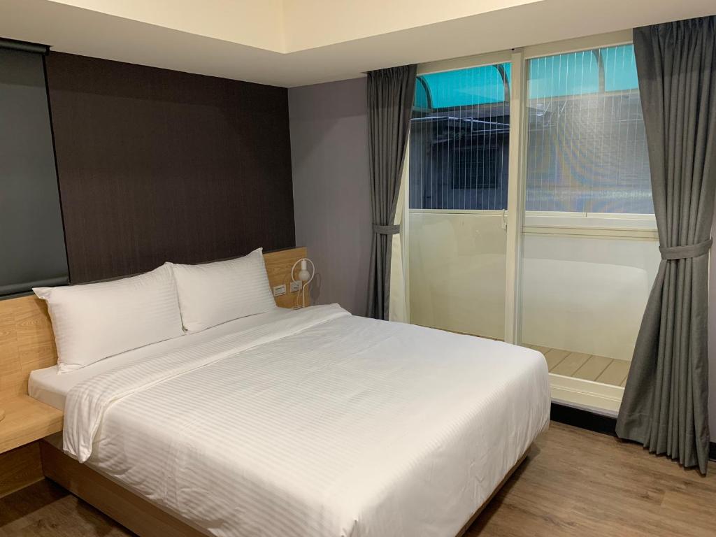 台北晴悦旅店的卧室设有一张白色大床和一扇窗户。