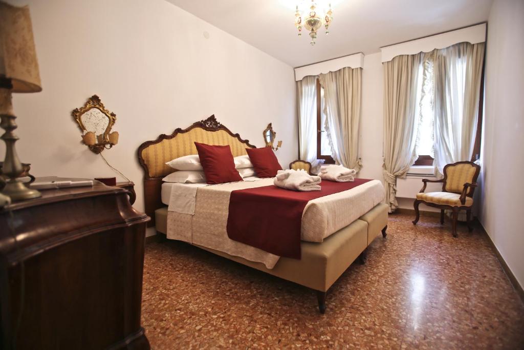 威尼斯Ca Donzela的一间卧室配有一张带红色枕头的床和梳妆台