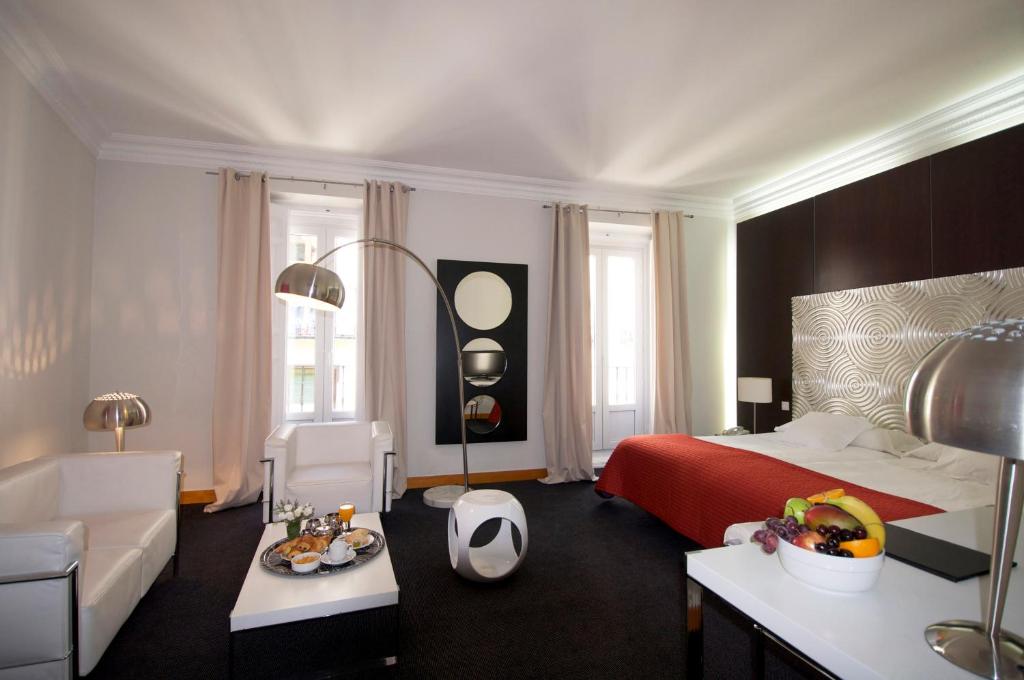 马德里普拉多套房酒店的一间卧室配有一张床、一张沙发和一张桌子