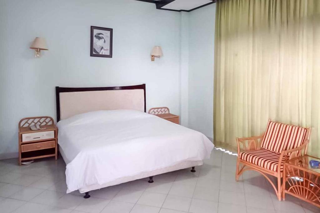 西冷RedDoorz Plus near Tugu Mercusuar Anyer的卧室配有白色的床和2把椅子
