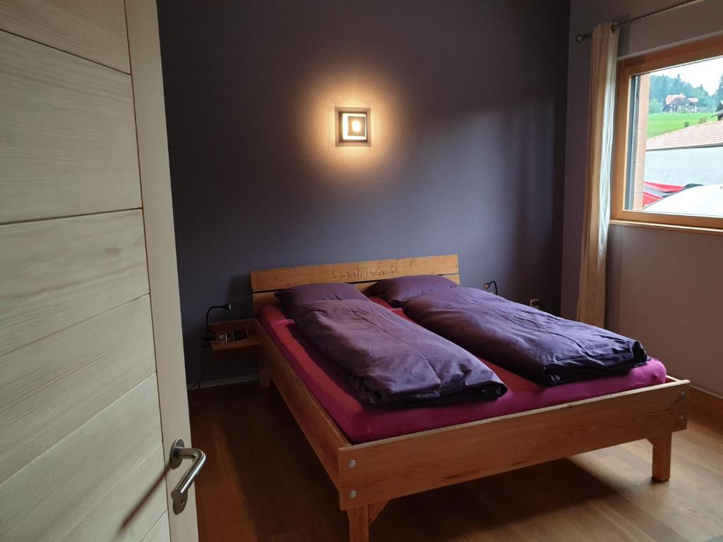 RüscheggGantrisch Lodge的一间卧室配有一张带紫色枕头的床