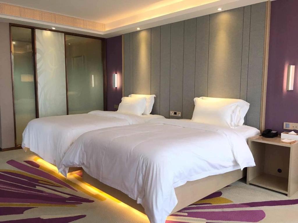 抚州Lavande Hotel (Fuzhou Wanda Branch)的配有白色床单的酒店客房内的两张床