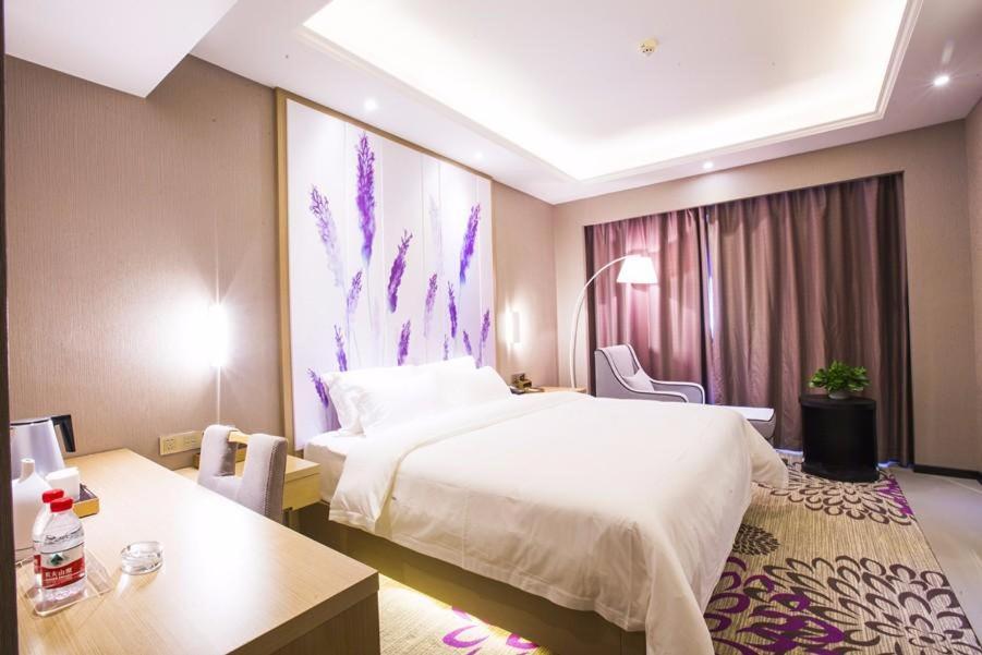 信阳Lavande Hotel Xinyang Municipal Government Branch的酒店客房设有一张大床和一张桌子。